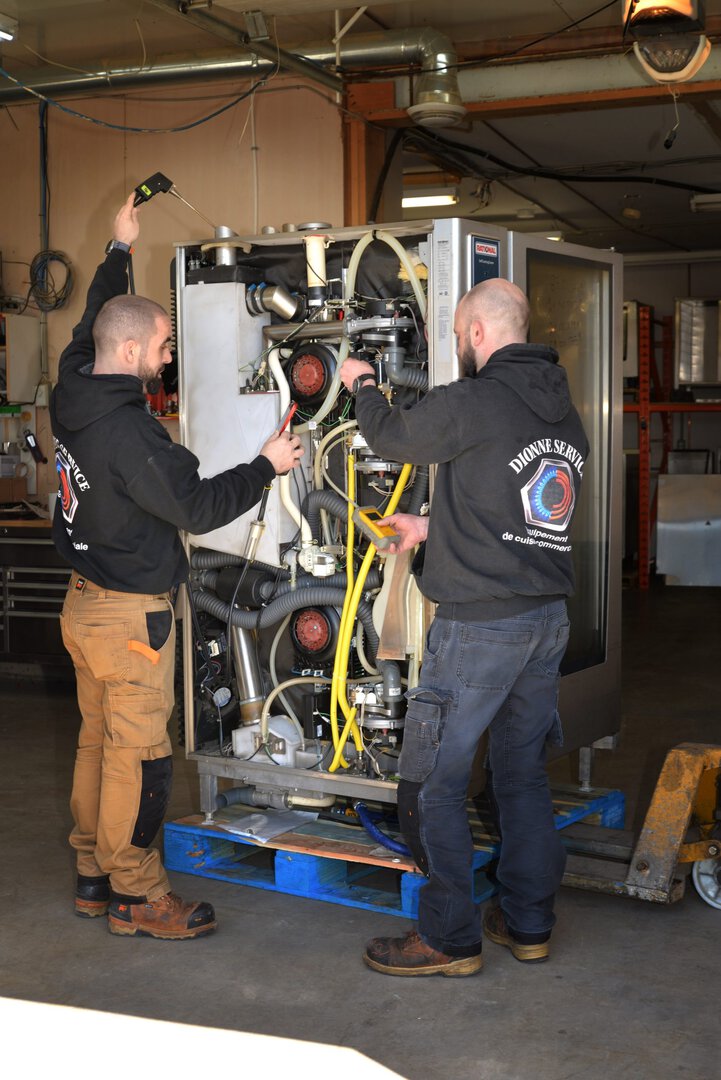 2 hommes réparent un four industriel