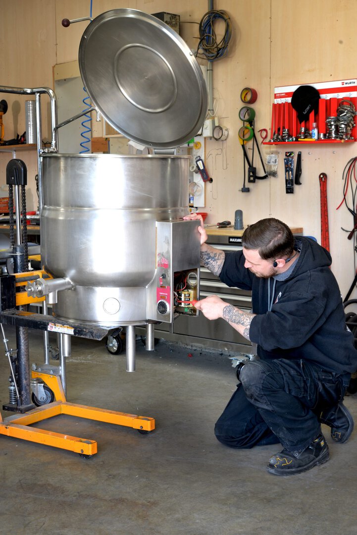 homme en train de faire des ajustements sur une grande cuve industrielle